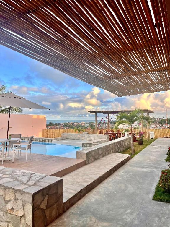 a patio with a pool and a table and an umbrella at Villa Mar - Baia Formosa in Baía Formosa