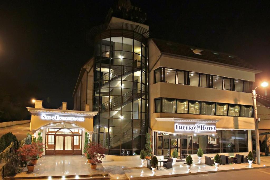 a large building with a store front at night at Hotel Impero in Oradea
