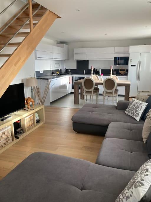 un salon avec un canapé et une table et une cuisine dans l'établissement Joli duplex proche du lac Léman, à Messery