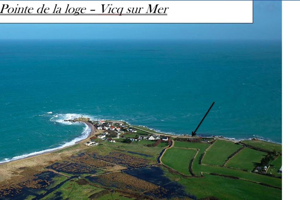 une île avec une éolienne dans l'océan dans l'établissement Les pieds dans l'eau - Cosqueville Vicq-mer, à Cosqueville