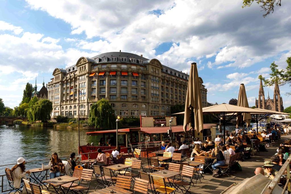 un groupe de personnes assises à des tables devant un bâtiment dans l'établissement Hyper Centre Krutenau Étoile Bourse Appart, à Strasbourg