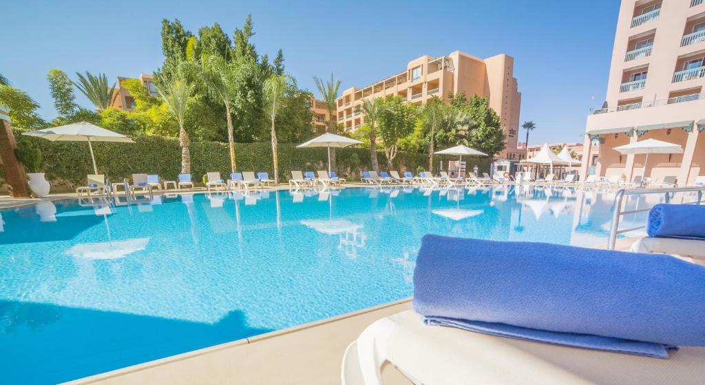 einen Pool in einem Resort mit Stühlen und Sonnenschirmen in der Unterkunft Grand Mogador Menara & Spa in Marrakesch