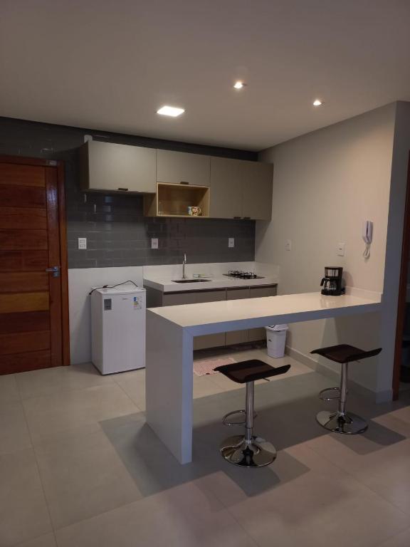a kitchen with a counter and two bar stools at Pousada Studio Flat Jequié in Jequié