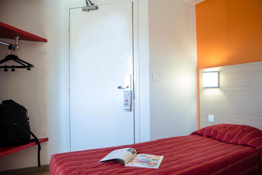 Un dormitorio con una cama roja con un libro. en HECO Calais Centre-Gare en Calais