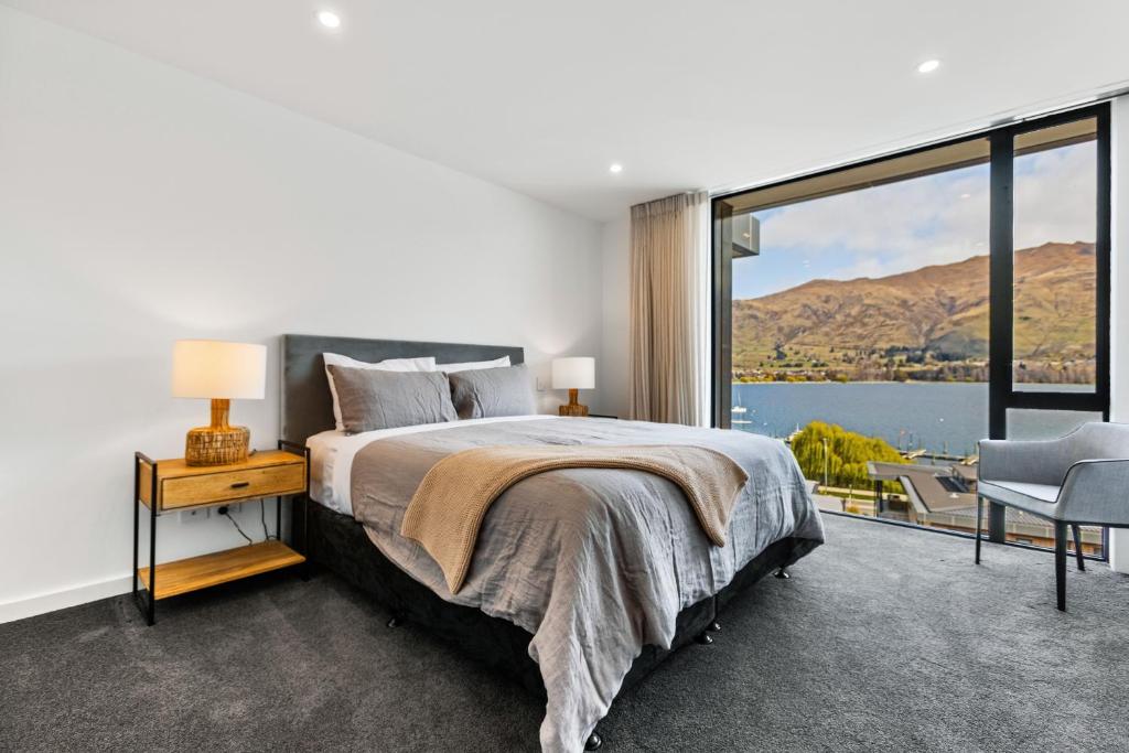 a bedroom with a bed and a large window at Penthouse with Marina Views - Studio or Two Bedroom Apartment in Wanaka