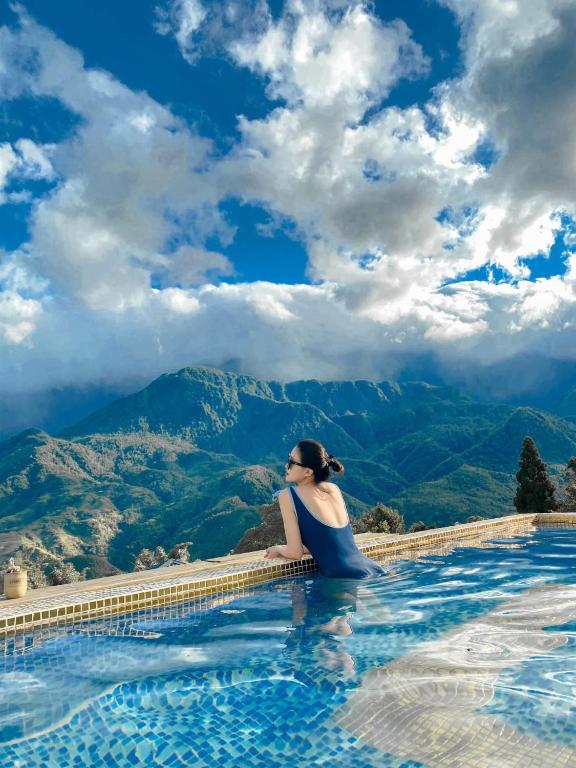 a woman sitting in a infinity pool with a view of mountains at The Upper House Sapa in Sapa