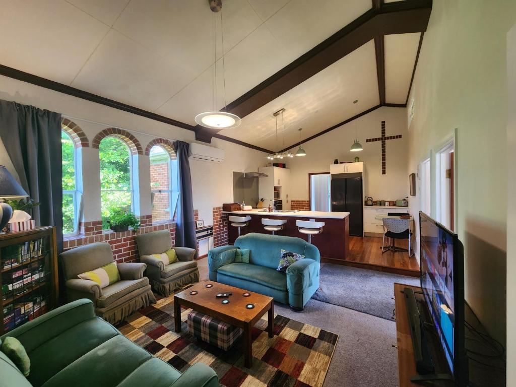 a living room with green furniture and a kitchen at The Church House- Boutique Comfort in Balclutha