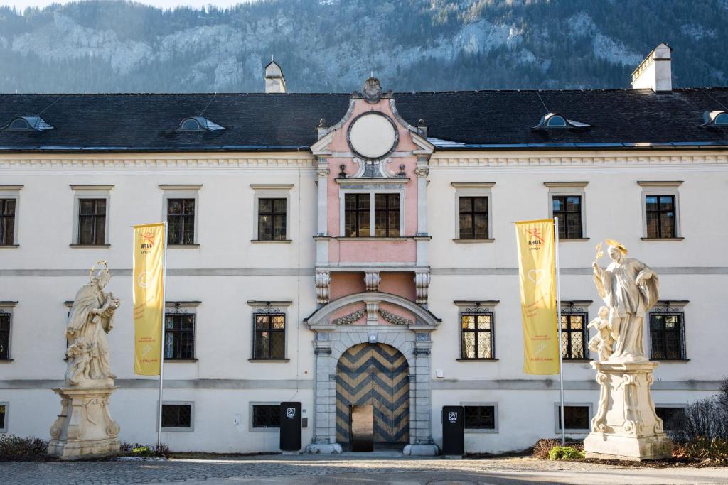 ein großes weißes Gebäude mit Flaggen davor in der Unterkunft JUFA Hotel Spital am Pyhrn in Spital am Pyhrn