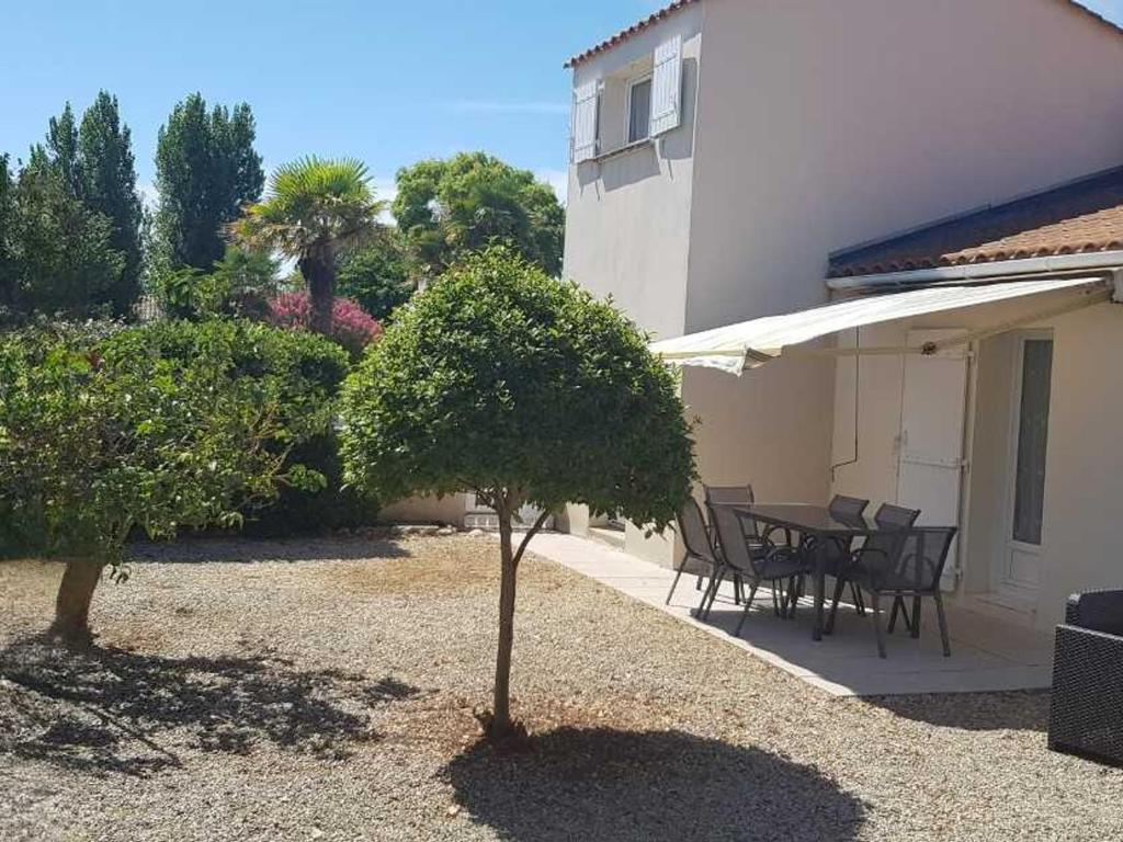 une terrasse avec une table et des chaises à côté d'une maison dans l'établissement Maison de vacances calme, proche plage, WiFi, animaux admis - FR-1-476-228, à La Faute-sur-Mer