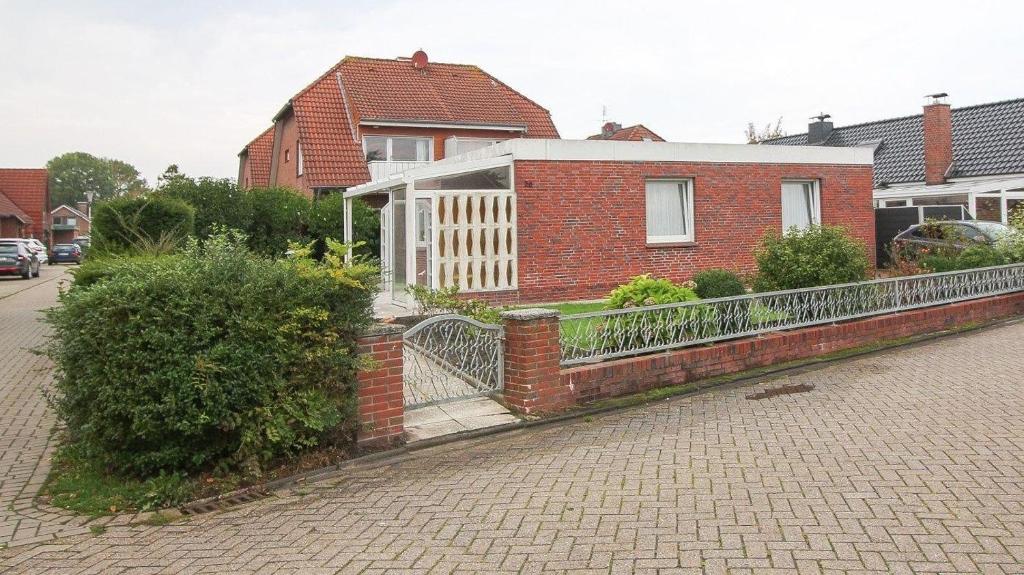 una casa de ladrillo con una valla delante en Bungalow-Marina, en Norddeich