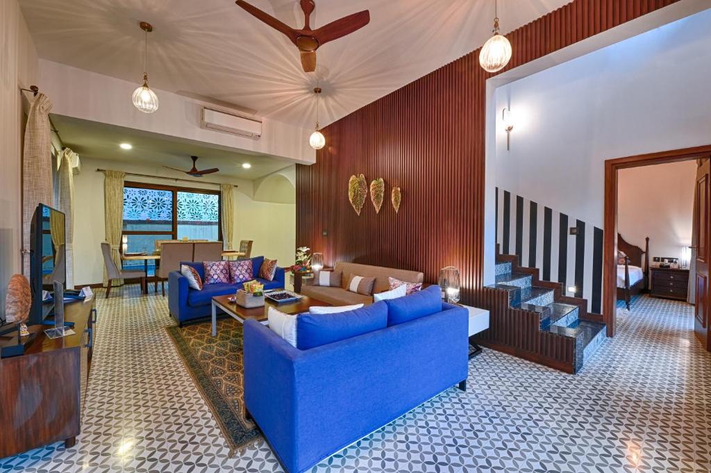 a living room with blue couches and a couch at Melhor Stays Villa - L-A3 Luxurious 3BHK villa with private pool, Assagao in Vagator