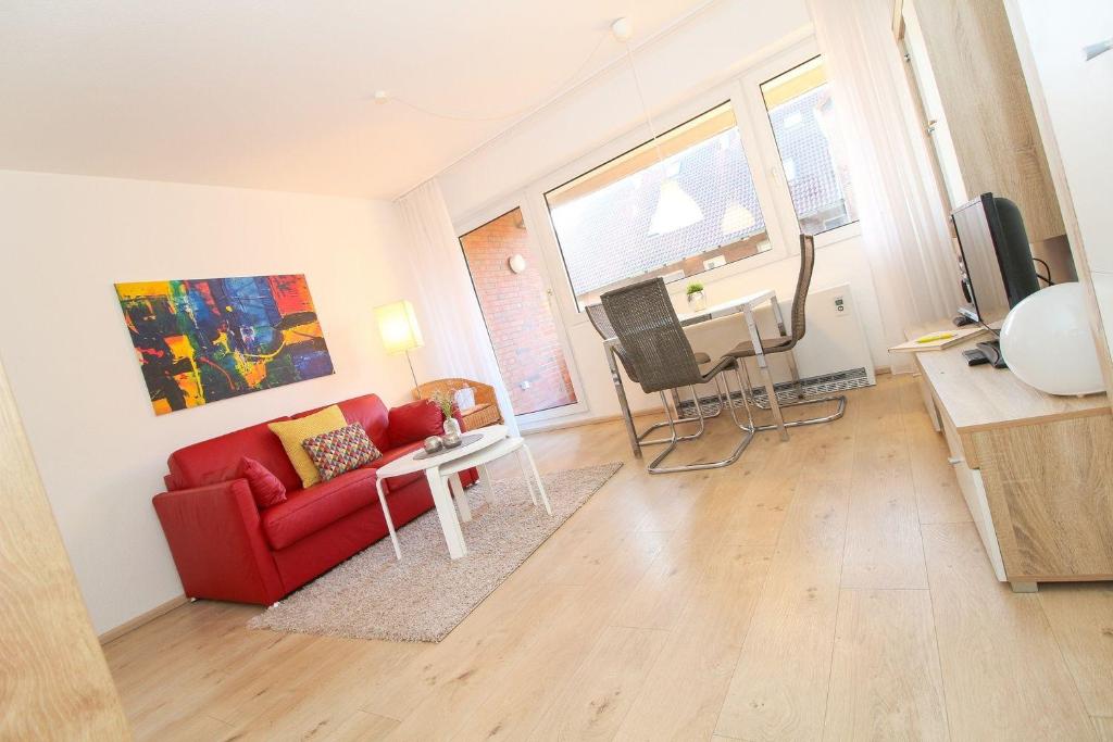 Una sala de estar con un sofá rojo y una mesa. en Westerriede, en Norddeich