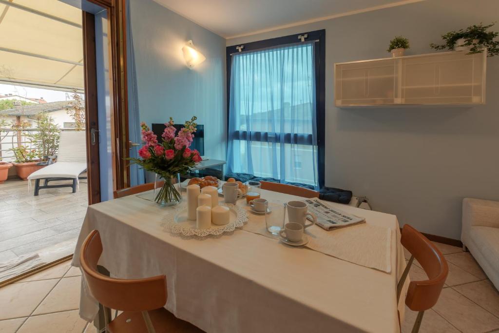 una mesa de comedor con un jarrón de flores y velas en Bellavista Apartment, en Marina di Ravenna