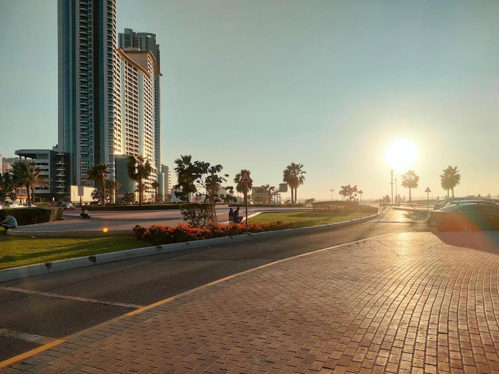 une rue vide dans une ville avec des bâtiments et le coucher du soleil dans l'établissement Charm - 2Bedrooms Apartment 3 beds 1 sofa bed, à Ajman