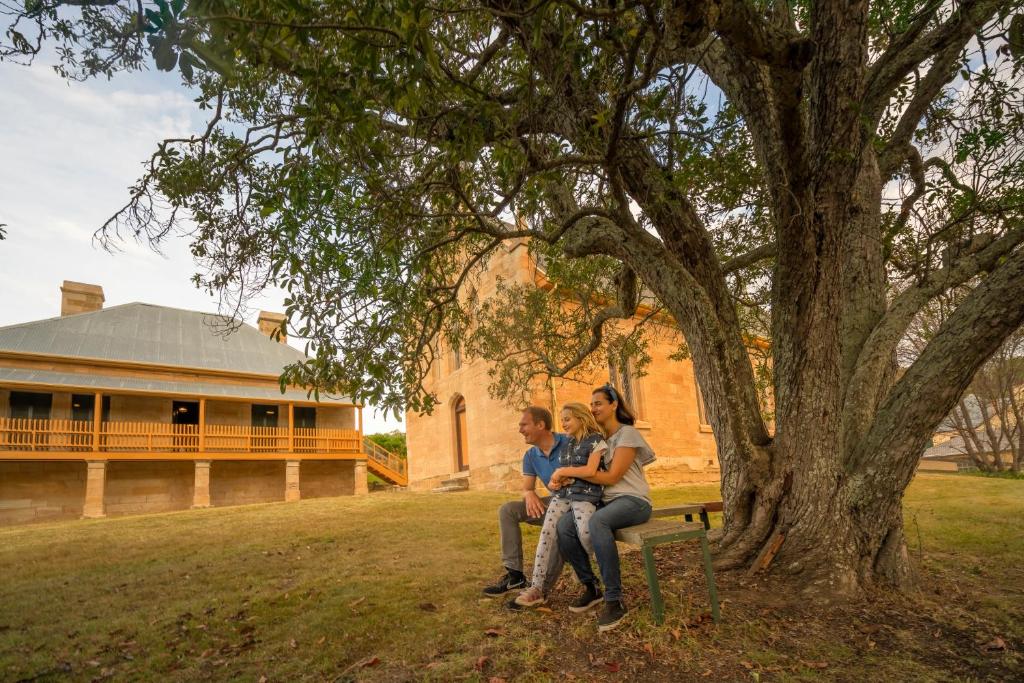 a group of people sitting on a bench under a tree at St Bernards Presbytery- Hartley Historic Site in Hartley