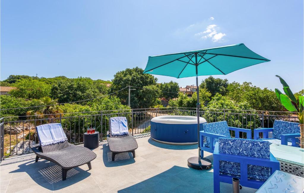 a patio with chairs and an umbrella and a hot tub at 2 Bedroom Cozy Home In Malinska in Malinska
