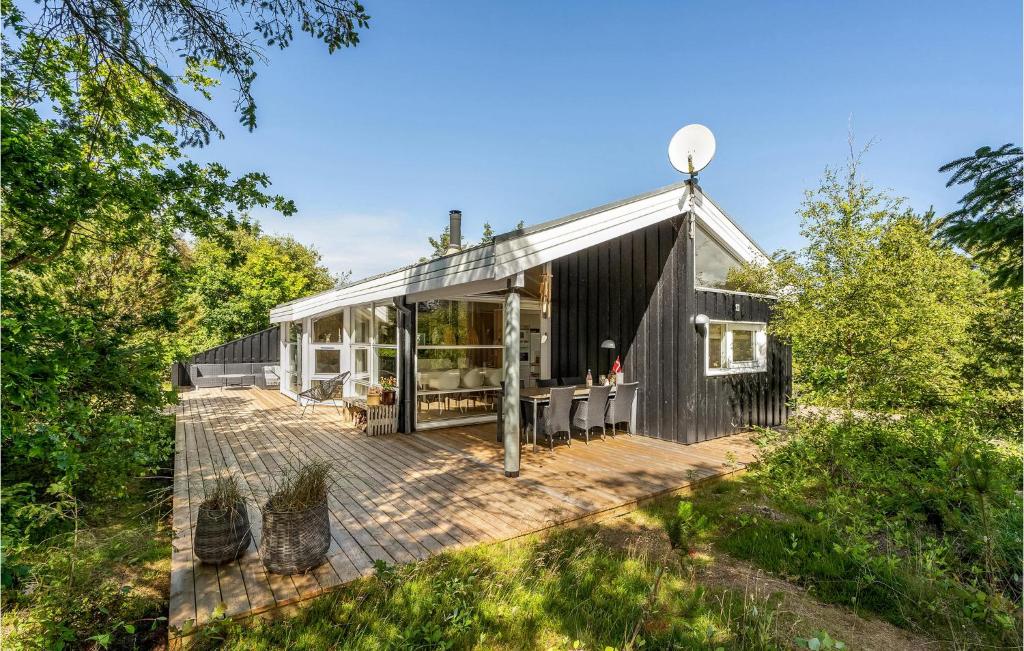 a black house with a deck in the woods at Nice Home In Vestervig With Wifi in Hinge