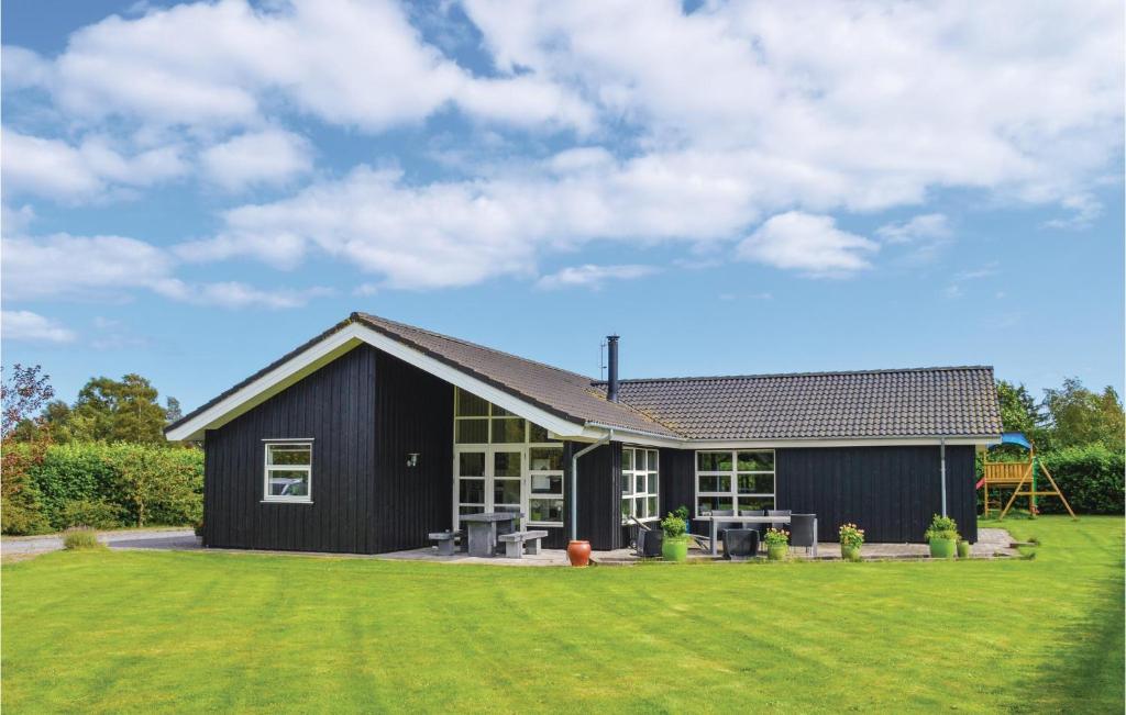 a black house with a large grass yard at Four-Bedroom Holiday Home In Storvorde in Storvorde