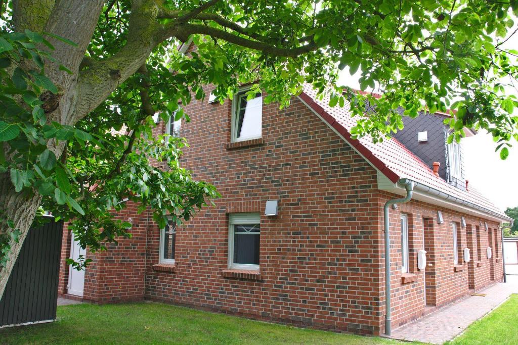 Un edificio de ladrillo con un árbol delante. en Friesenstrasse, en Norden