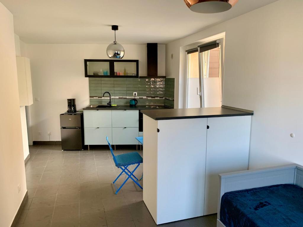 une cuisine avec un comptoir et une chaise bleue dans une pièce dans l'établissement Paris Express studio 5 min on foot to tube station, aux Lilas