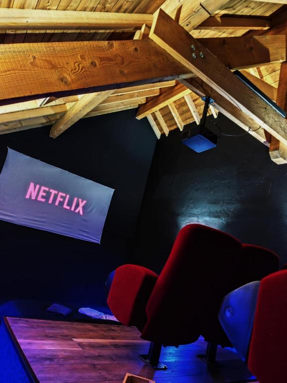 une chambre avec un panneau netflix et des chaises dans l'établissement LE COCON l'unique expérience Cinéma room de la Grange Savoyarde 1km du Lac d'Annecy, à Lathuile