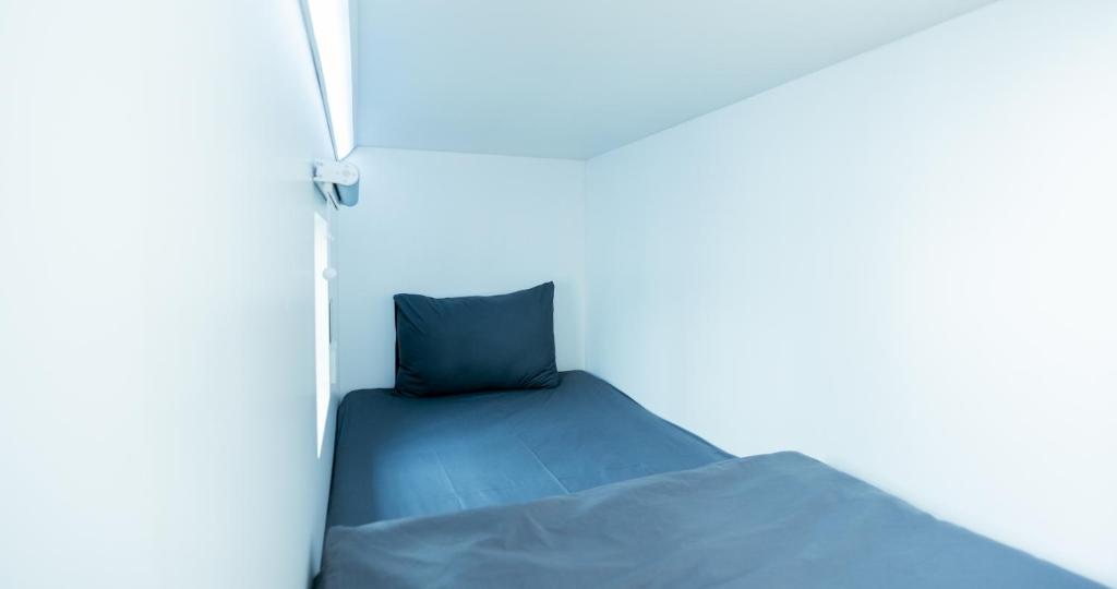 a bed with a blue pillow in a room at Bobopod Kota Tua, Jakarta in Jakarta
