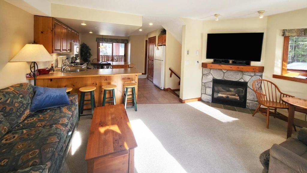 a living room with a couch and a kitchen with a fireplace at Timberline Village #46 home in Sun Peaks
