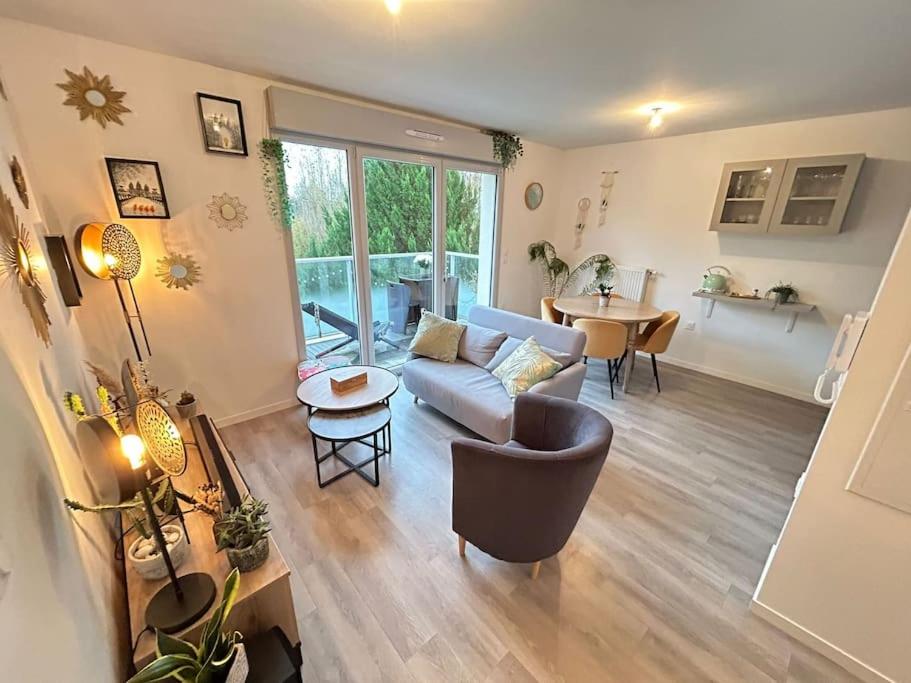 una sala de estar con un sofá y una mesa en Appartement récent tout confort, en Caen