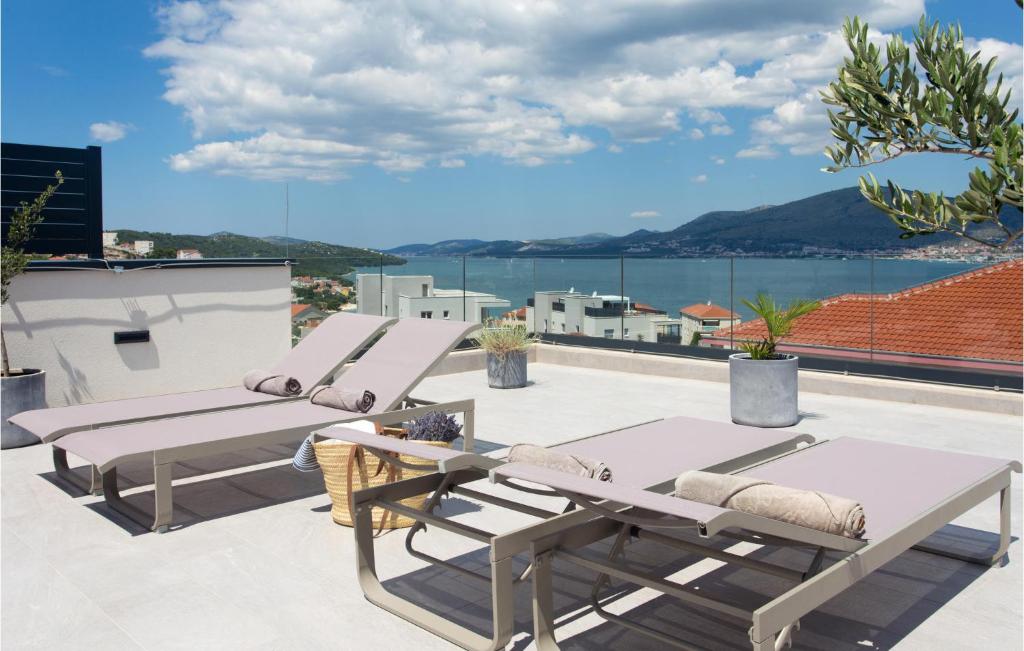 a patio with lounge chairs and a view of the water at Gorgeous Apartment In Okrug Gornji in Trogir