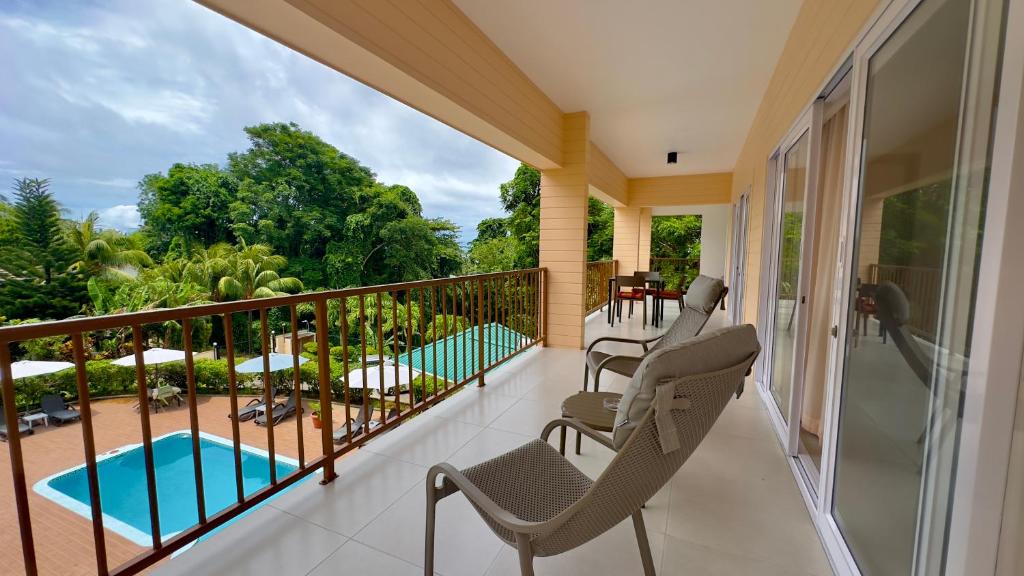 a balcony with chairs and a swimming pool at The Palm Seychelles in Bel Ombre