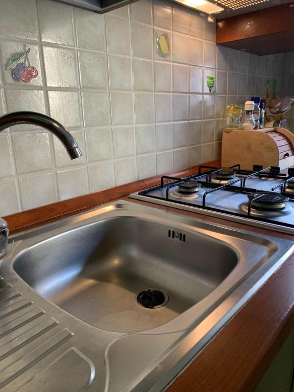 zlew ze stali nierdzewnej w kuchni z kuchenką w obiekcie Appartamento Casa Trento w mieście Castellammare del Golfo