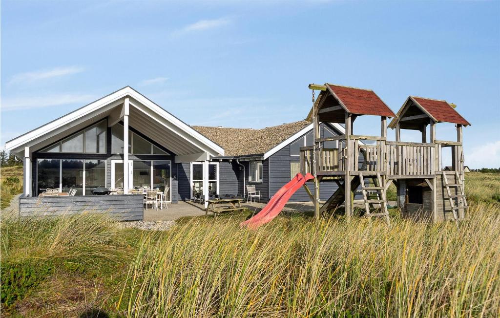 a house with a playground in front of it at Awesome Home In Ringkøbing With Sauna in Klegod