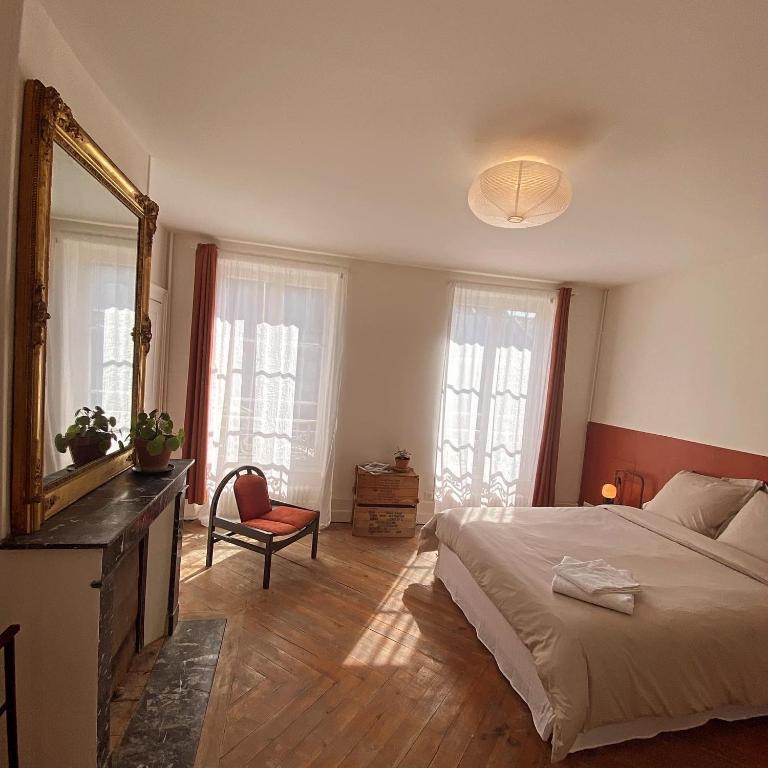 une chambre avec un grand lit et un miroir dans l'établissement La Maison des Ifs Terracotta, à Mamers