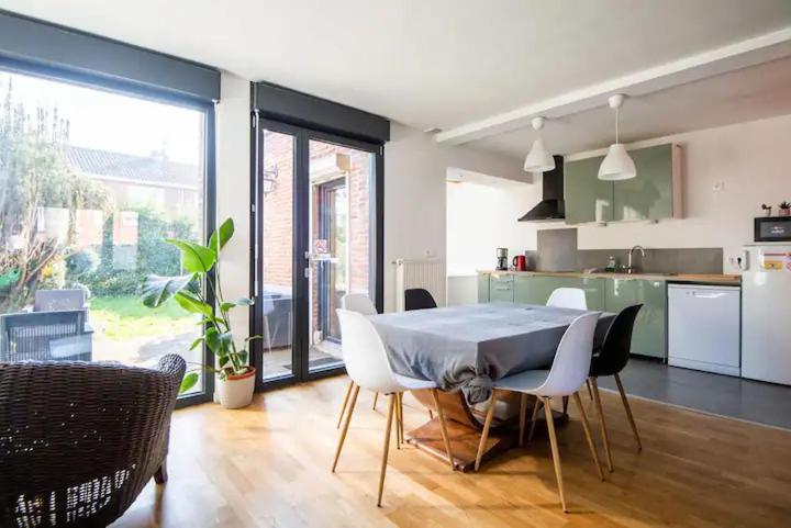 una cucina e una sala da pranzo con tavolo e sedie di Maison à l'orée du BOIS CITADELLE de LILLE avec TERRASSE en plein sud PROCHE DE TOUTES COMMODITES à la porte de LILLE a Lambersart