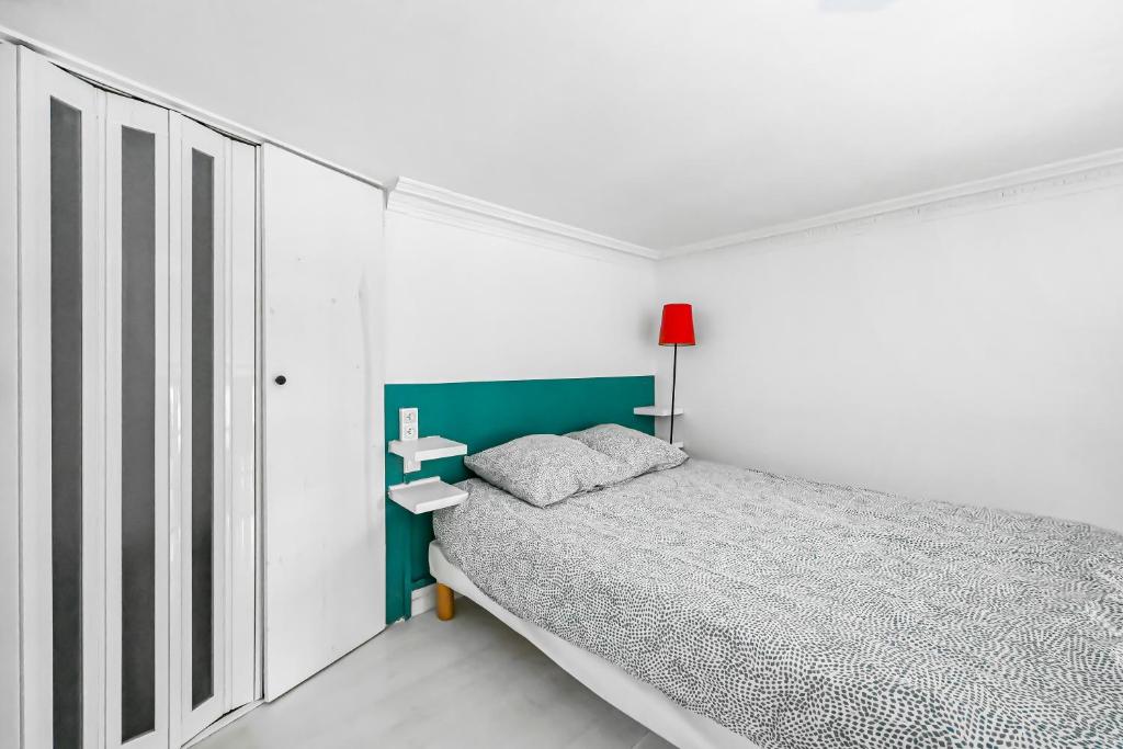 - une chambre blanche avec un lit et une tête de lit verte dans l'établissement Chambre cosy dans petit loft, à Paris