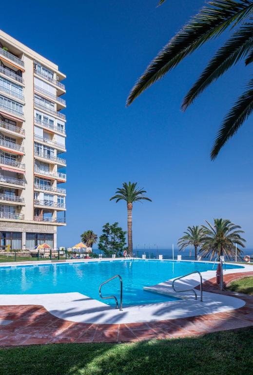 basen z palmami przed budynkiem w obiekcie Exclusivo apartamento con increíbles vistas al mar w mieście Torremolinos