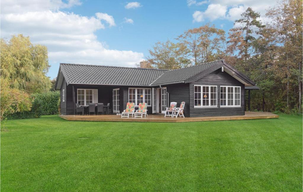 a small black house with chairs on a lawn at Awesome Home In Græsted With Wifi in Græsted