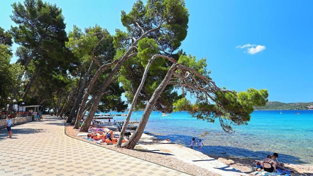 a beach with people laying on the sand and the water at Danyja Mobilehome in Biograd na Moru