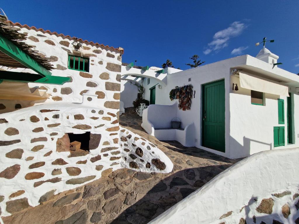 a white building with a green door and a staircase at Small cozy house Susana in Mogán