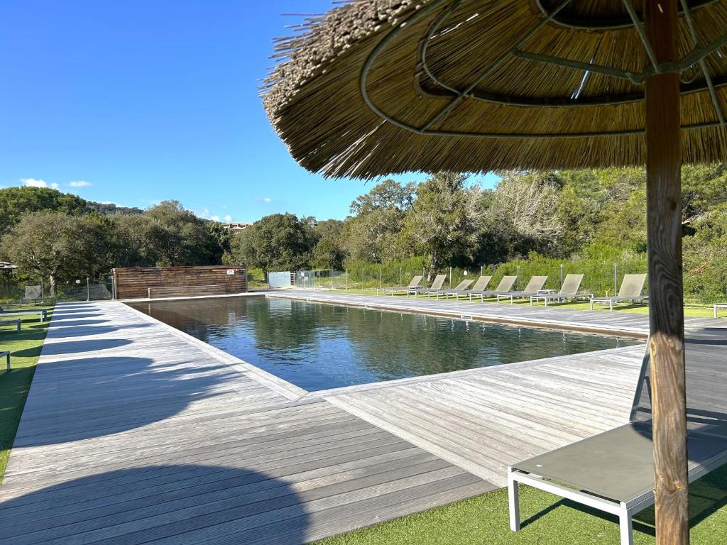 une terrasse en bois avec un parasol et une piscine dans l'établissement Appartement 4 étoiles piscine et plage à pied, à Porto-Vecchio