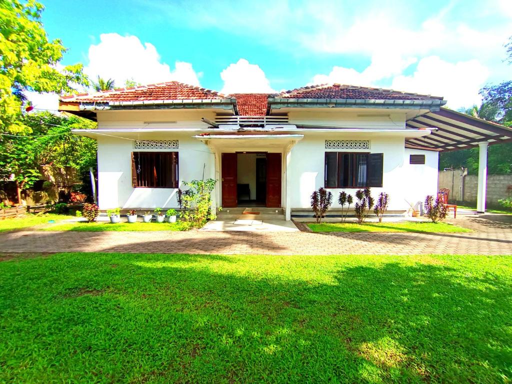 una casa blanca con césped delante en Shine Breeze villa, en Ahangama