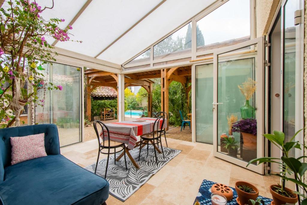 einen Wintergarten mit einem Tisch und Stühlen auf einer Terrasse in der Unterkunft Maison Calme et Sérénité - Welkeys in Montpellier