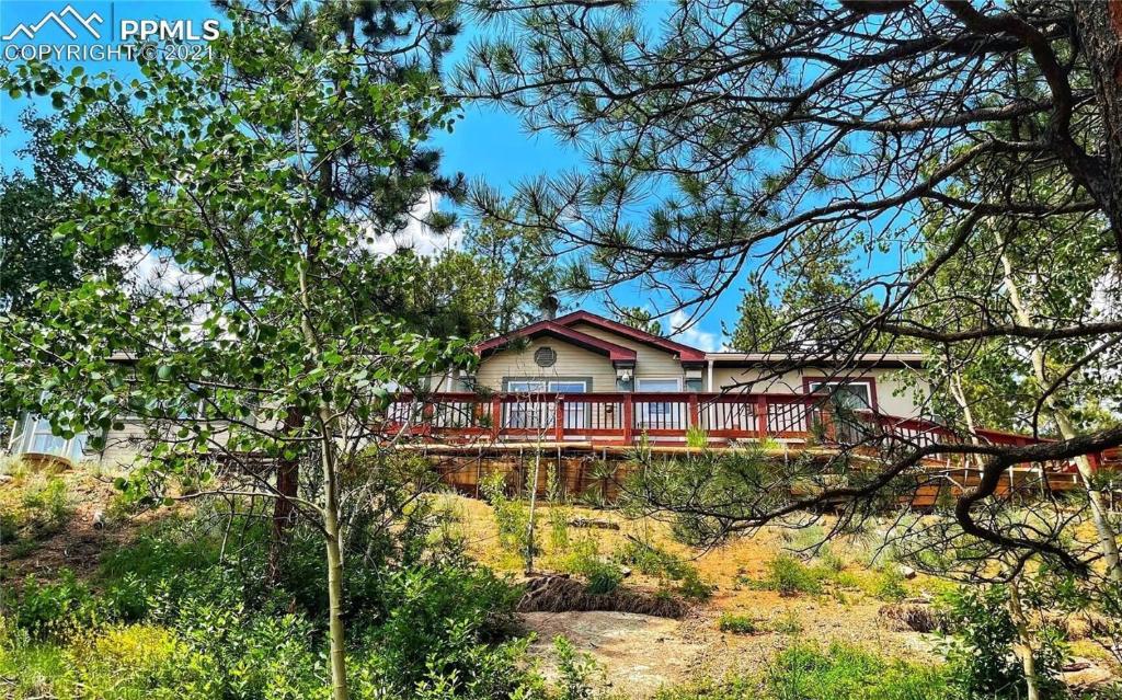 una casa con una terraza roja en el bosque en Mountain Cabin Retreat, en Florissant