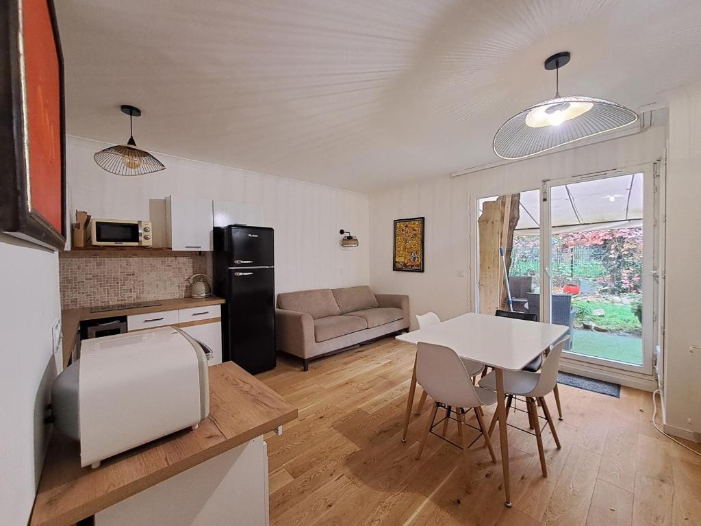 une cuisine et un salon avec une table et des chaises dans l'établissement Appartement avec jardin, à Paris
