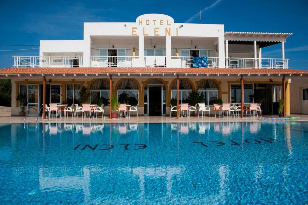 un hôtel avec une piscine en face d'un bâtiment dans l'établissement Eleni Hotel, à Kefalos