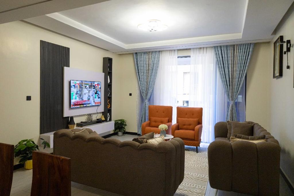 カンパラにあるA home away from homeのソファ2脚と薄型テレビのあるリビングルーム