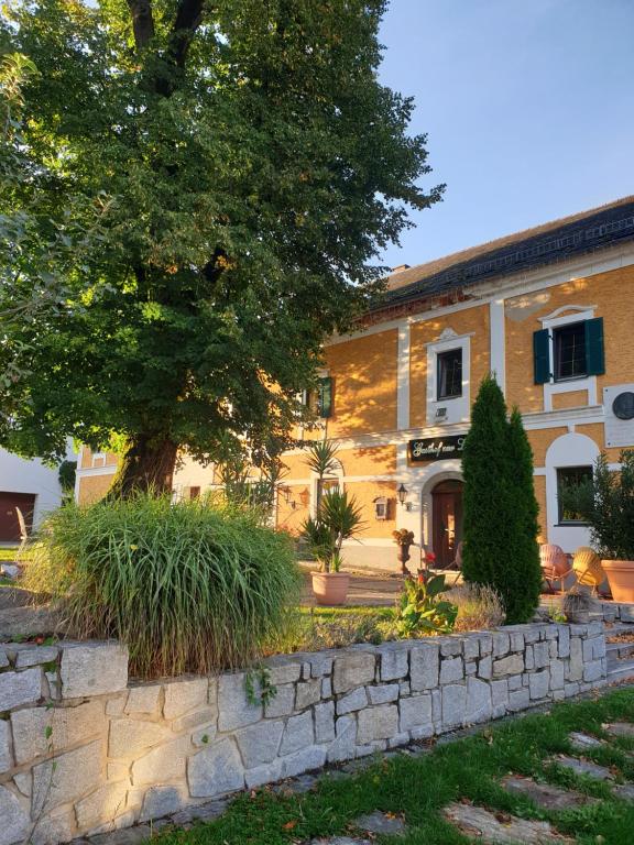 a building with a tree and a stone wall at LINDENGUT - Boutique Hotel nahe IKUNA Park in Natternbach