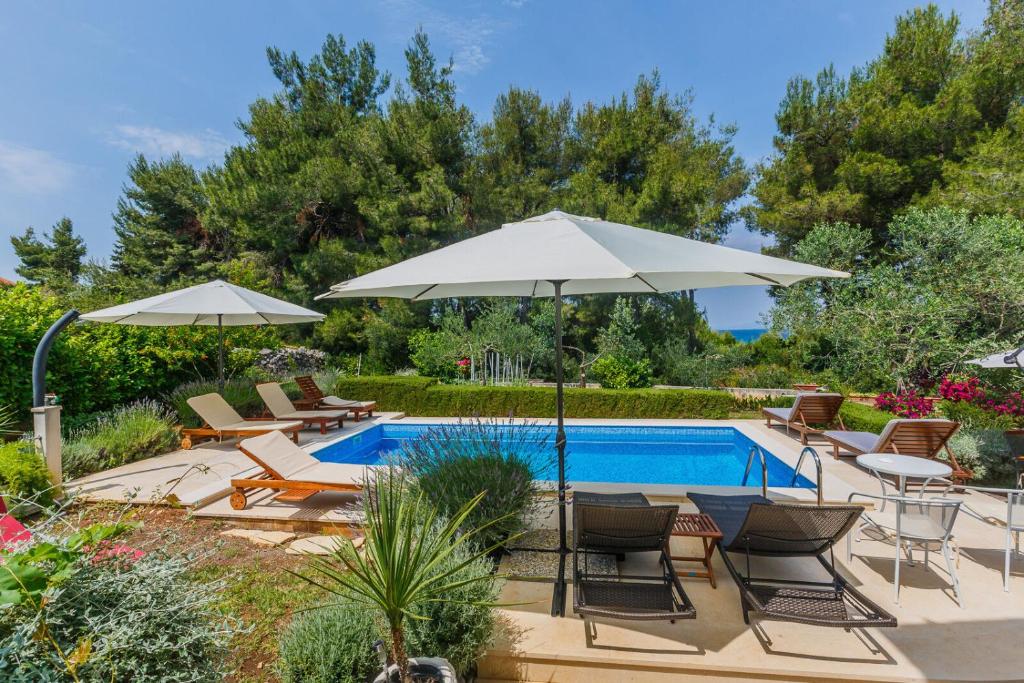 a swimming pool with chairs and umbrellas next to a pool at House Sanda in Mirce