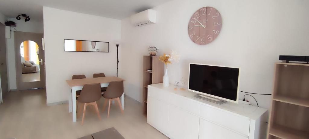 - un salon avec une télévision, une table et une horloge dans l'établissement APPARTEMENT 4 à 6 Pers, au Cap d'Agde