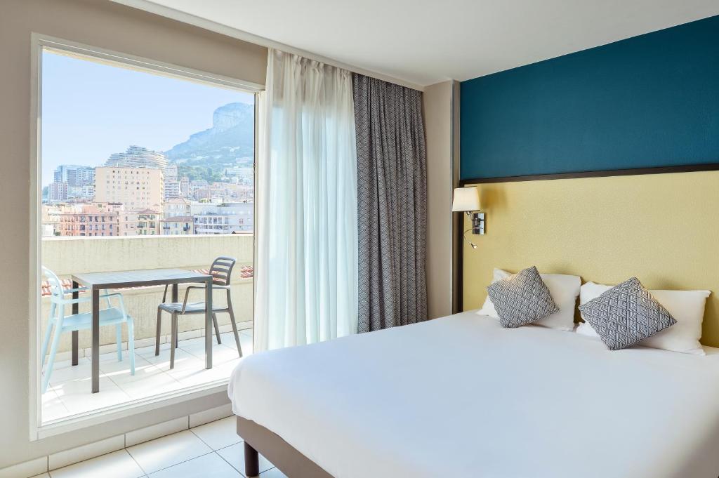 une chambre d'hôtel avec un lit et une grande fenêtre dans l'établissement Aparthotel Adagio Monaco Monte Cristo, à Beausoleil
